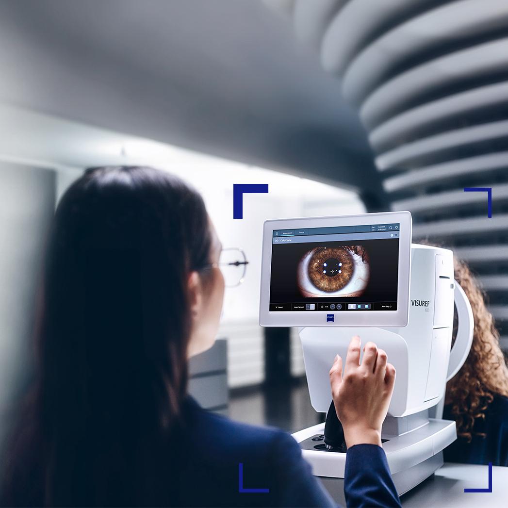 En kvinnelig optiker ser på ZEISS VISUREF 600-skjermen som viser et bilde av et øye.
