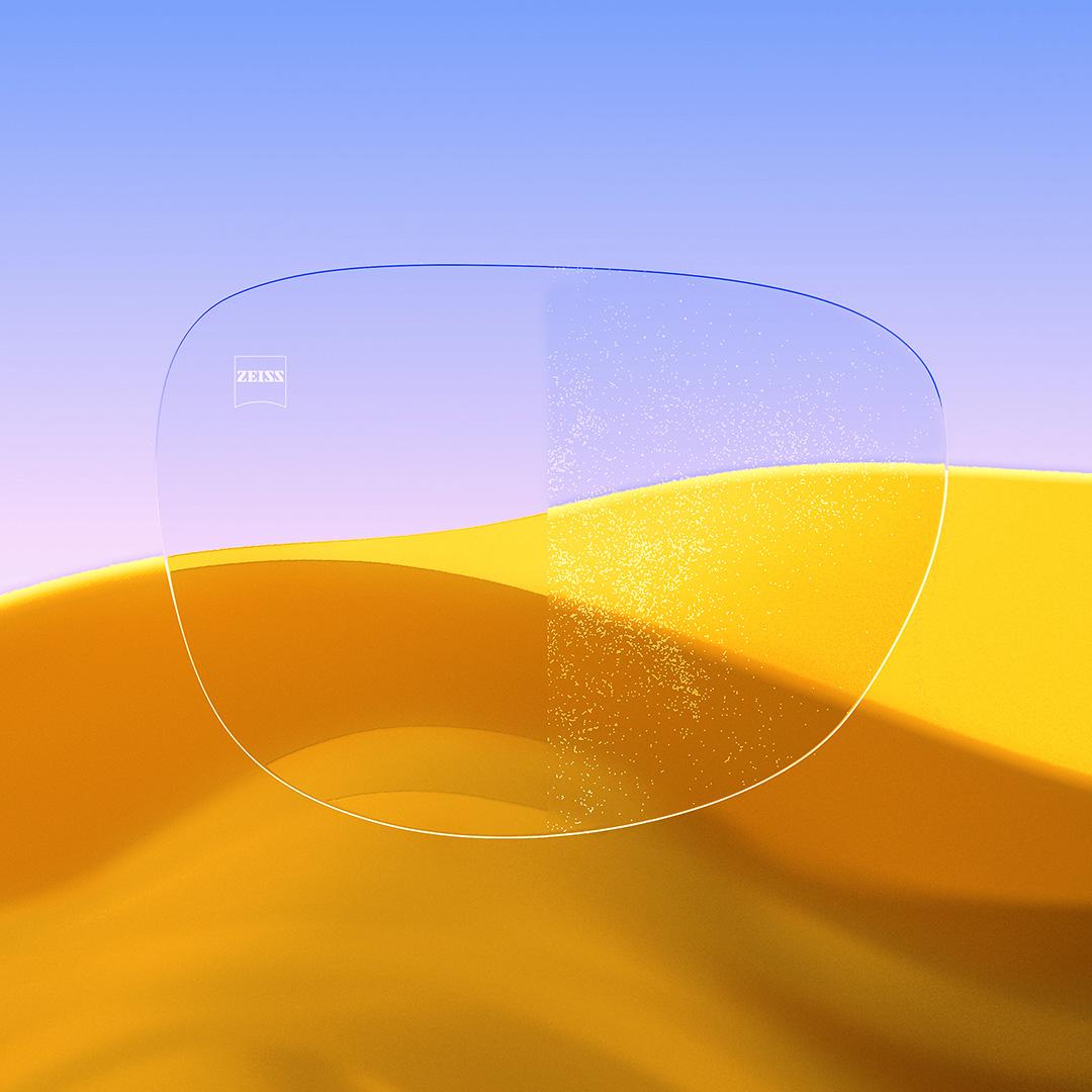 Et delt brilleglass der den ene siden er klar og ren med ZEISS DuraVision Gold UV, mens den andre siden et dekket av støv.