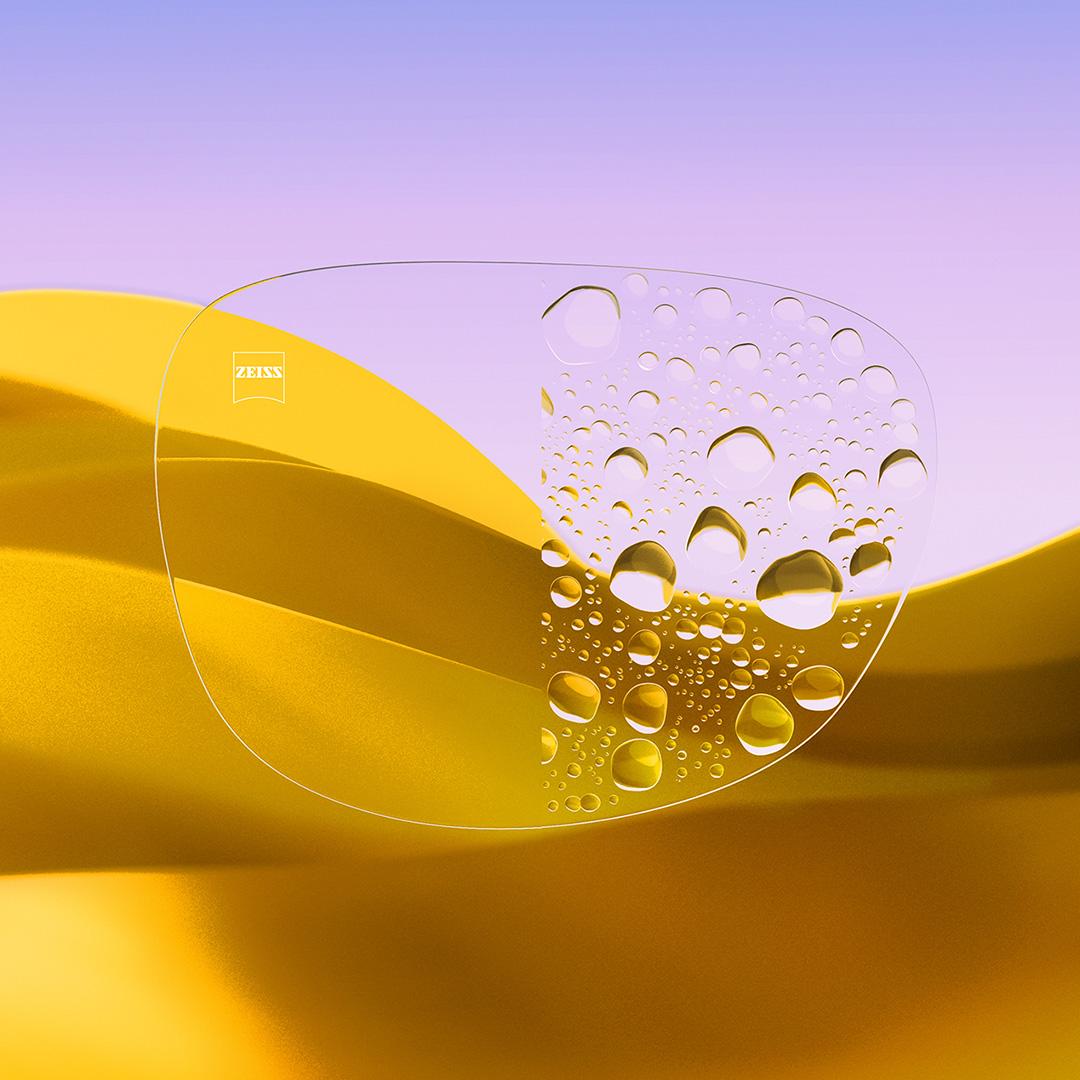 Et delt brilleglass der den ene siden er klar og ren med ZEISS DuraVision Gold UV, mens den andre siden et dekket av vanndråper.
