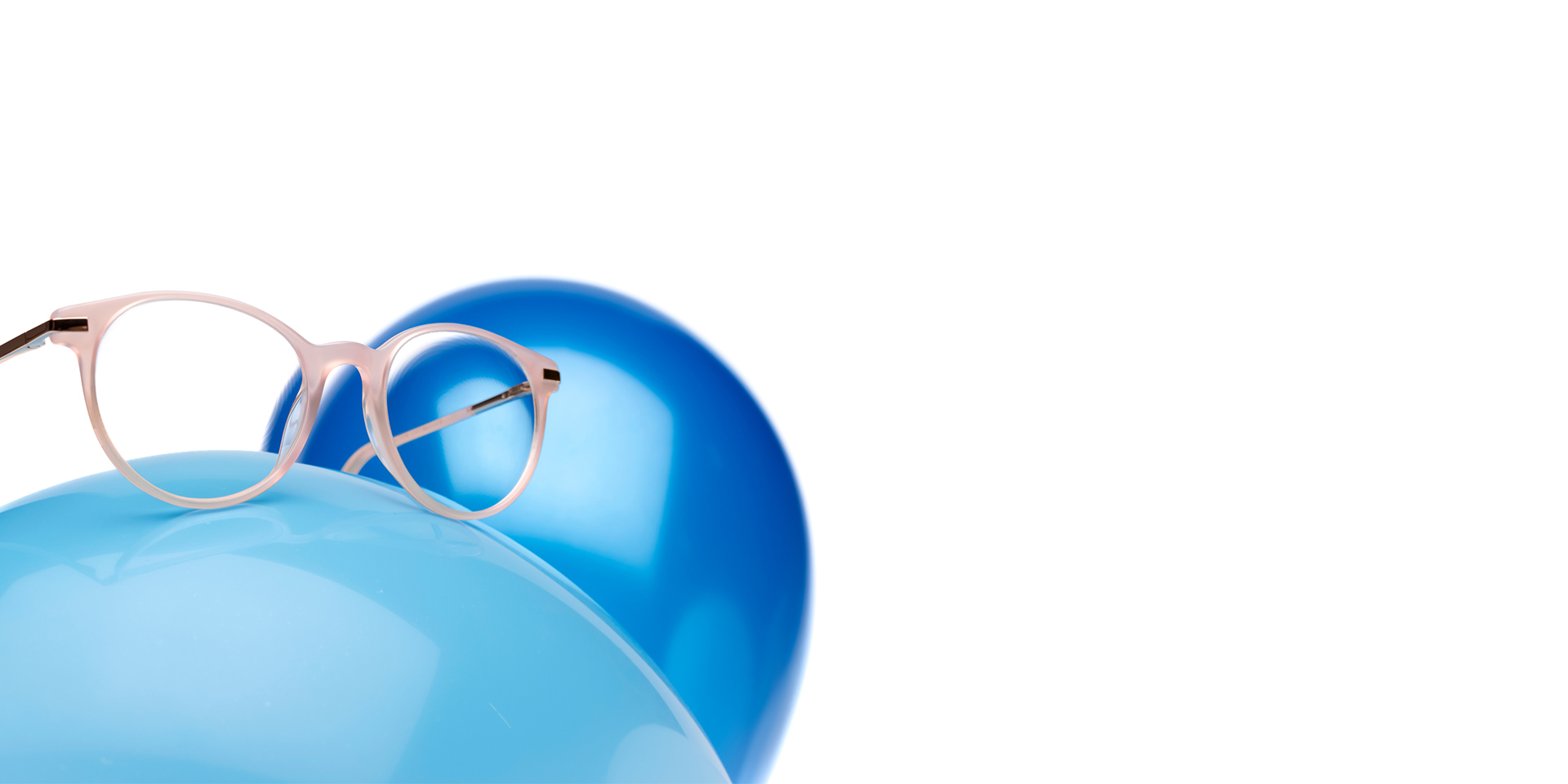 ZEISS MyoCare-glass i en beige innfatning vises på en lyseblå ballong. I bakgrunnen er en annen litt mørkere blå ballong.