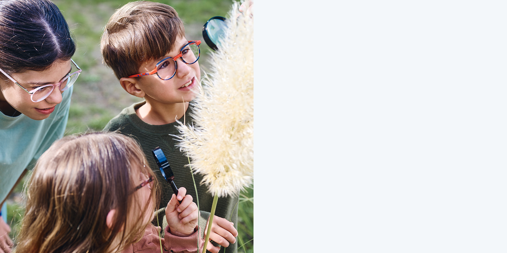 2 jenter og 1 gutt som bruker ZEISS MyoCare-glass. De ser på en plante, to av de tre barna ser på planten gjennom forstørrelsesglass.