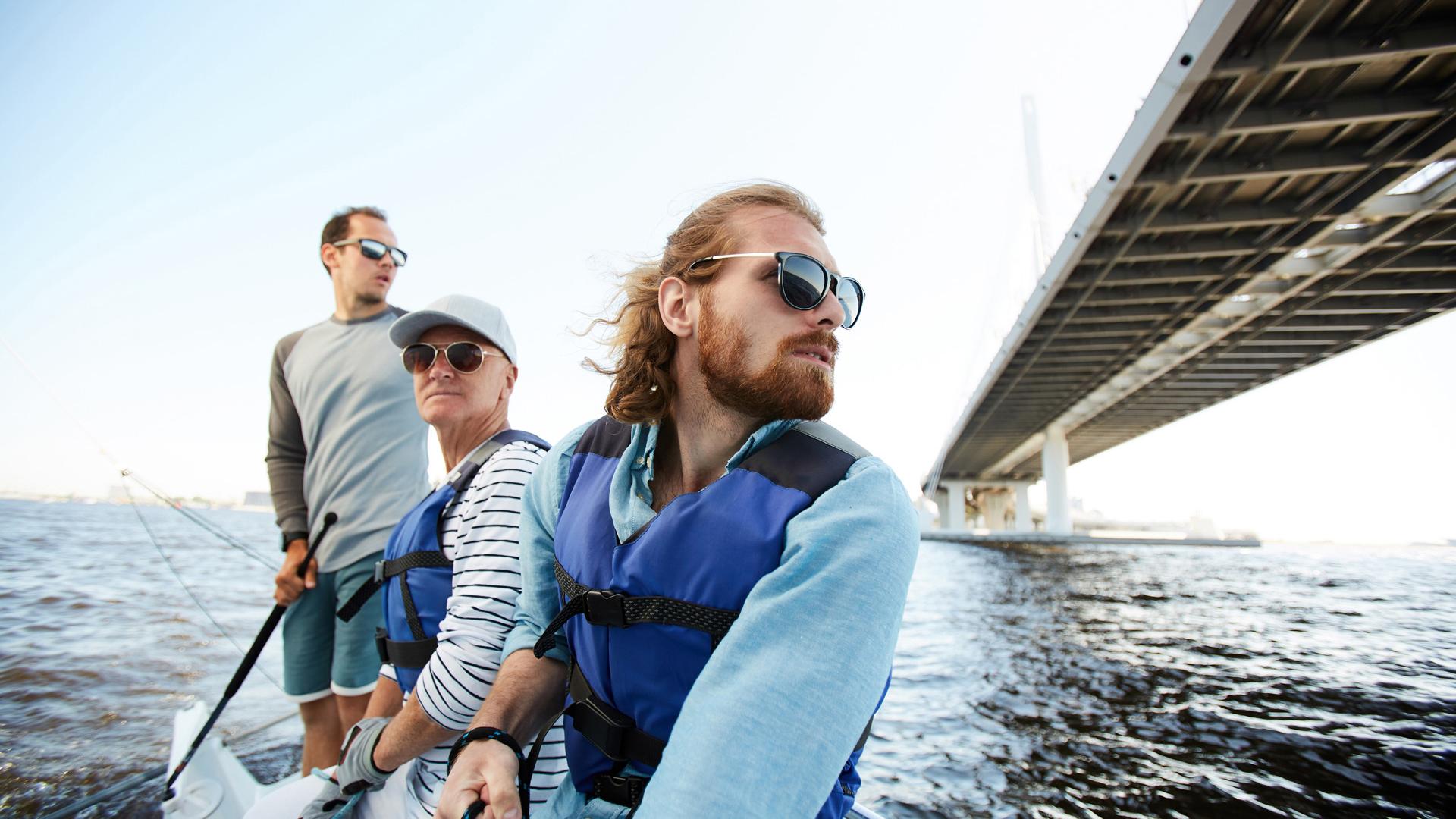 Menn med solbriller som seiler en yacht