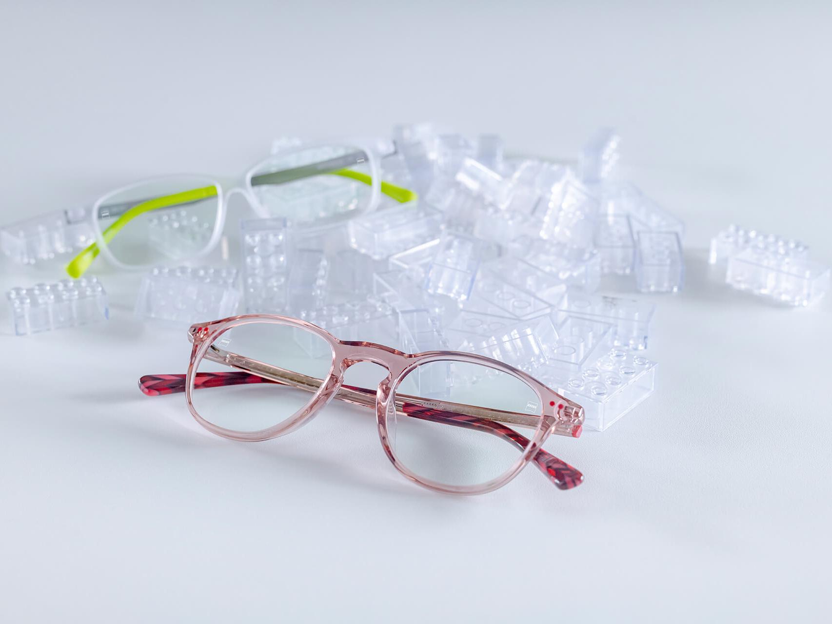 To par barnebriller med ZEISS-glass og DuraVision® barnebelegg. Glassene er plassert mellom gjennomsiktige barneklosser.