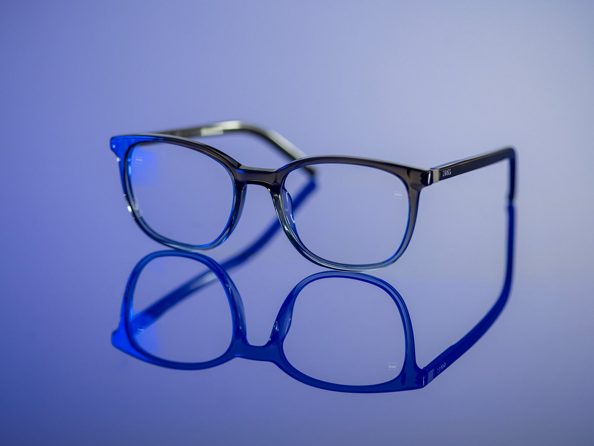 Briller som kan sees i blåaktig lys og har ZEISS-glass med BlueGuard glassmateriale. Bare en svært redusert blålig refleksjon er synlig på glassene.