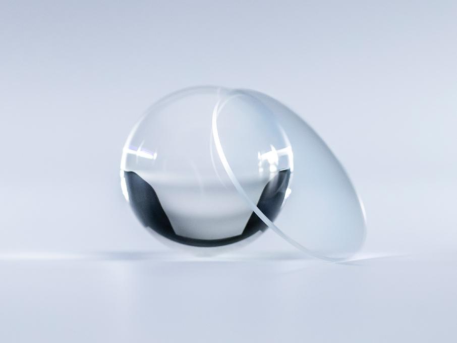 Et brilleglass med ZEISS Platinum-belegg er krystallklart uten refleksjoner sammenlignet med glasskulen ved siden av.