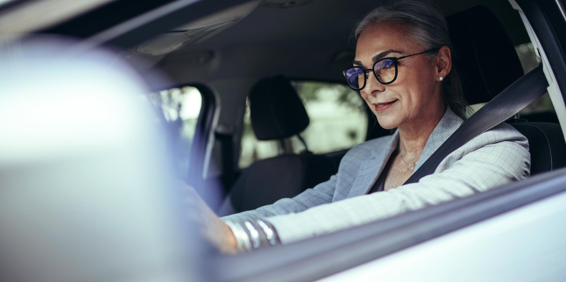 En moden kvinne i en bil har på seg briller med ZEISS DriveSafe-glass.