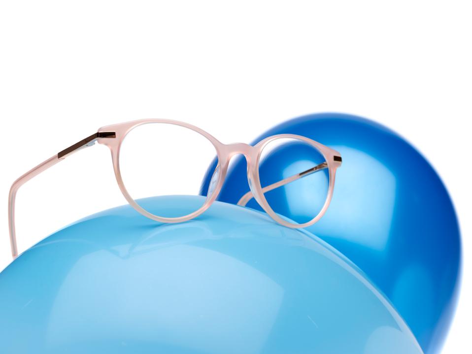 Rosa brilleinnfatning med ZEISS MyoCare-glass på en blå ballong.