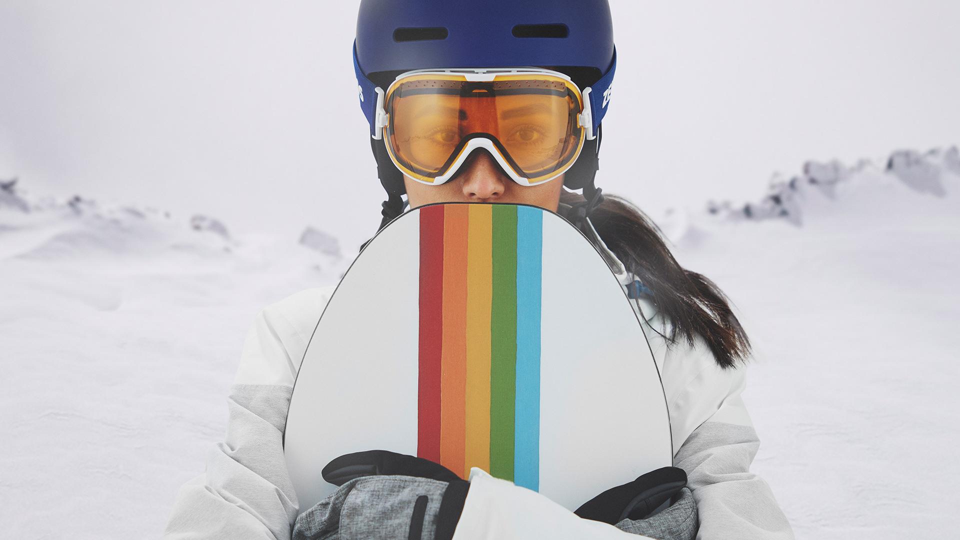 En ung kvinner bruker skibriller med ZEISS teknologi med utskiftbare glass og holder et snowboard.