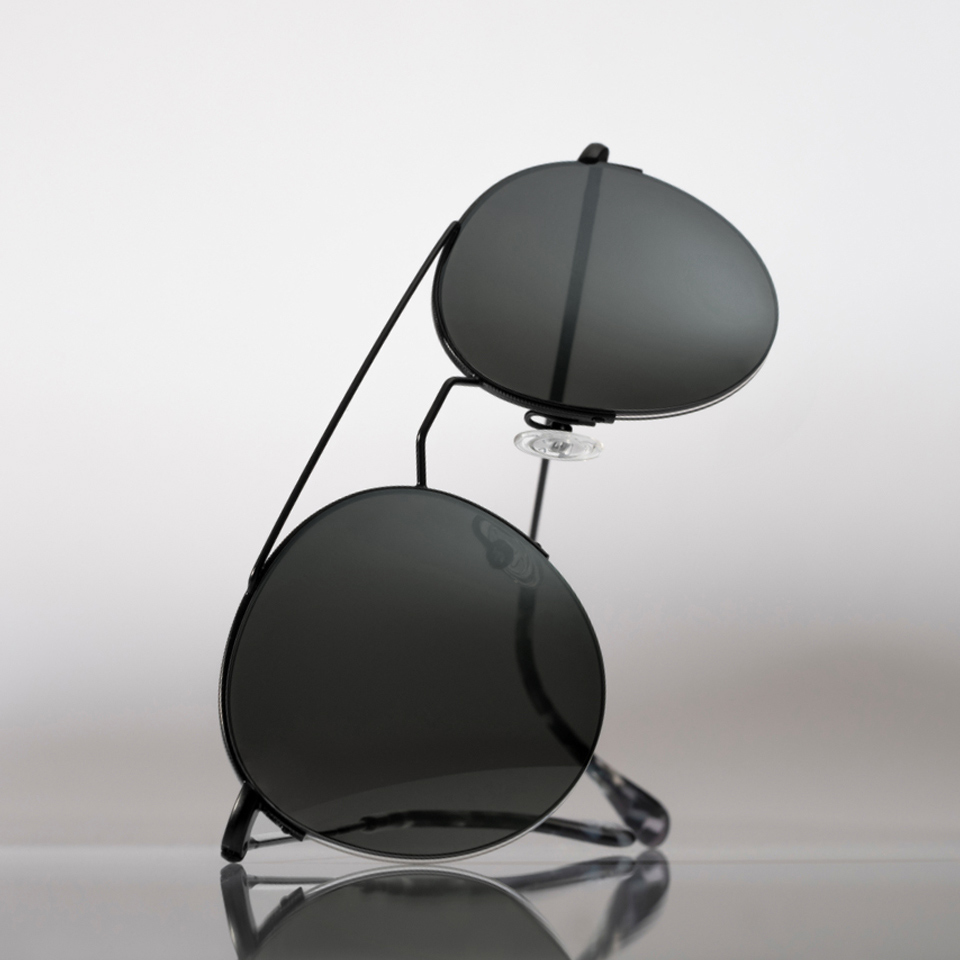 Solbriller med grå fargetone ligger på en ren, lett overflate.