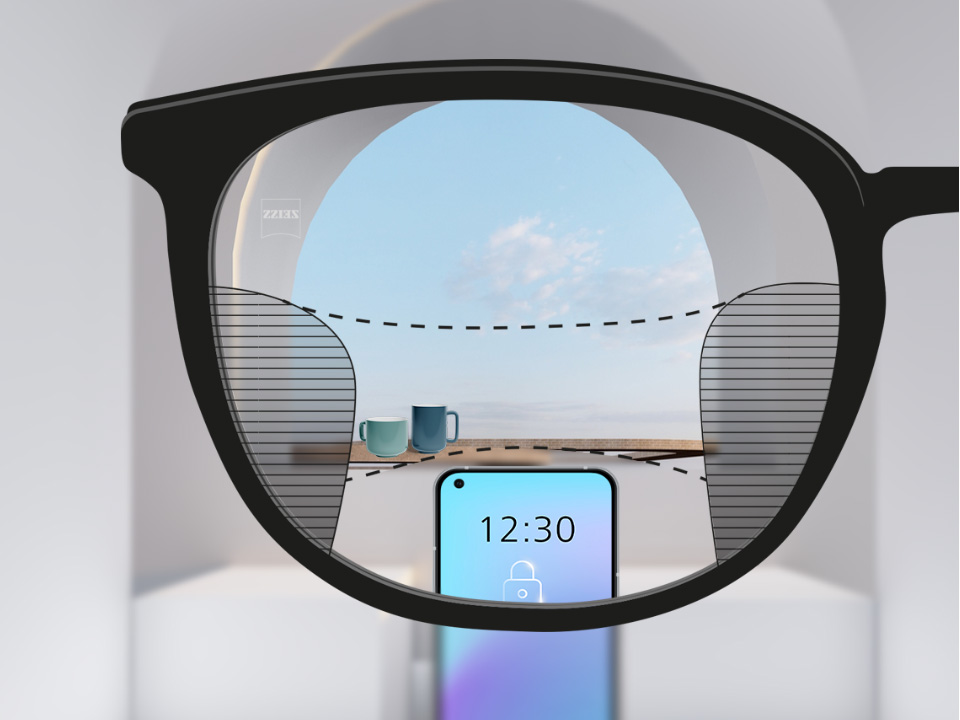 Et perspektivbilde med ZEISS progressive SmartLife-glass med en smarttelefon og kopper i bakgrunnen mens glasset er helt klart med slanke uskarpe plott til venstre og høyre.
