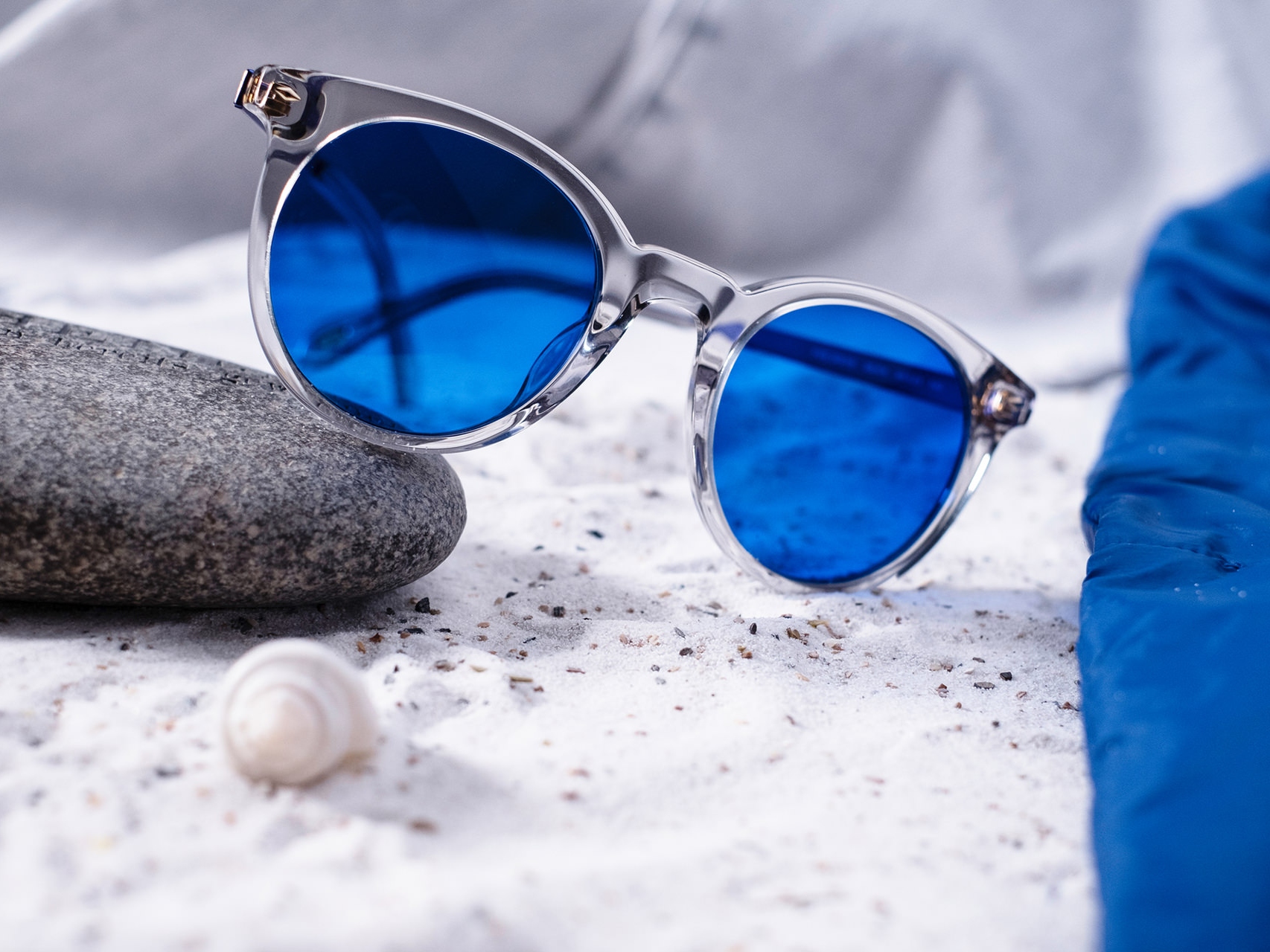 Bilde av et par solbriller med blå fargetone halvveis lagt på en stein