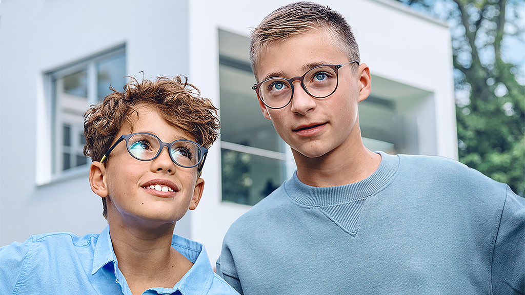 En ung gutt som ser opp til en tenåringsgutt, begge med ZEISS enstyrke SmartLife Young-briller
